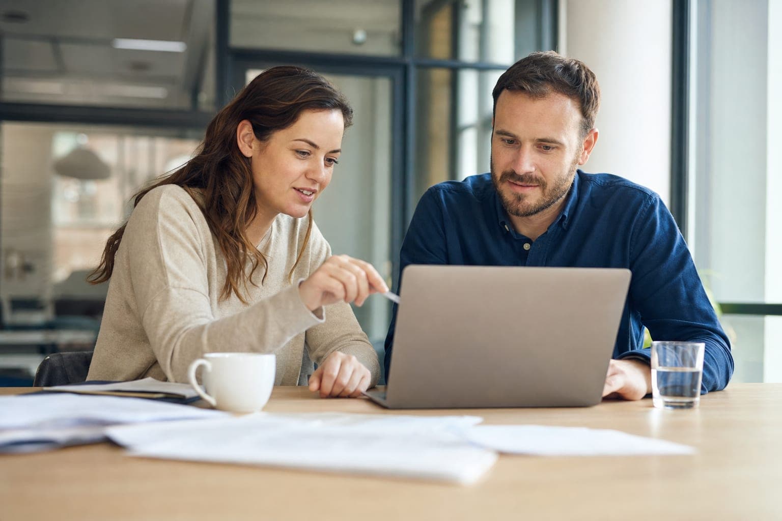 Zwei Personen im Büro besprechen am Laptop die offene Stelle